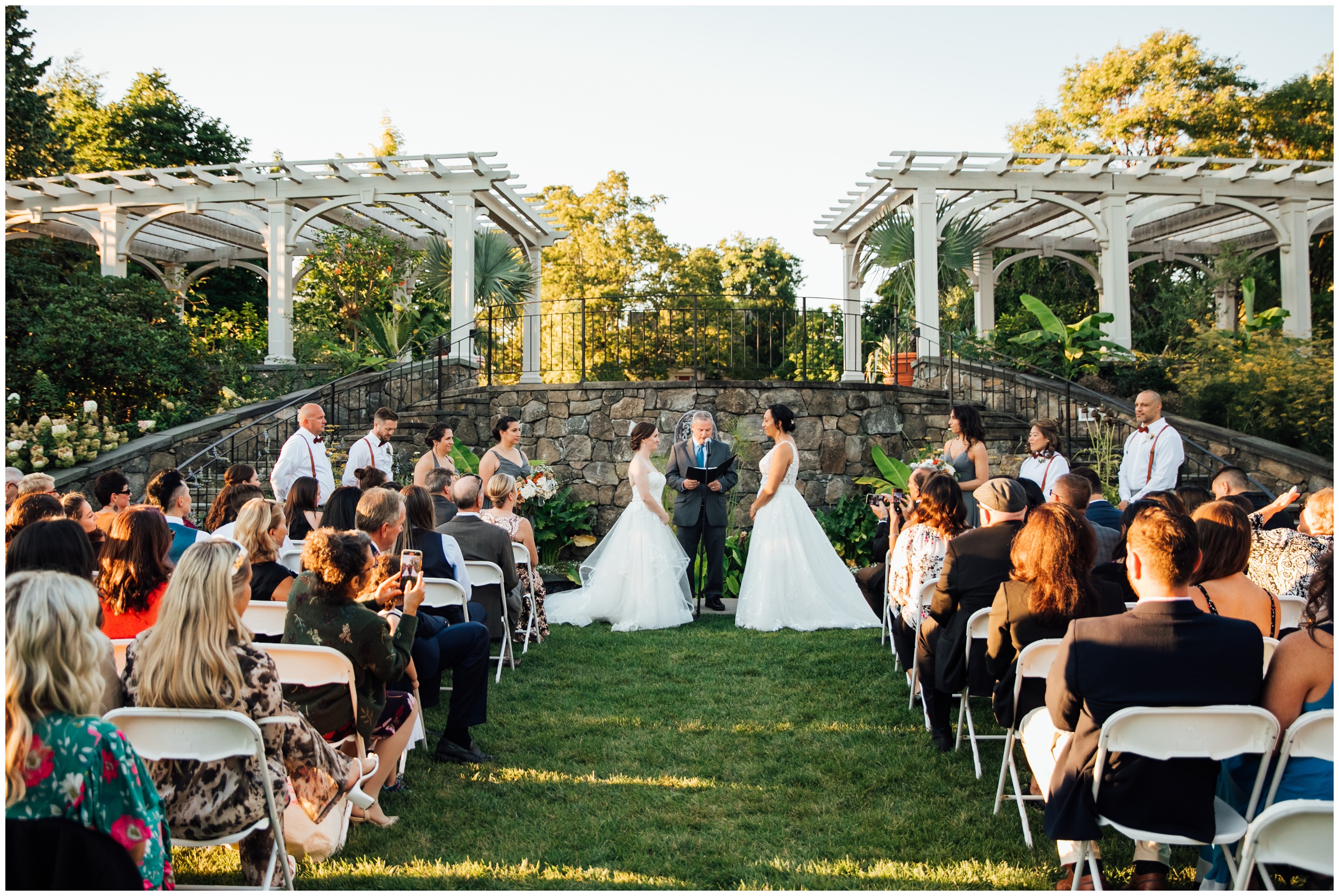 Two brides exchanging vows during outdoor ceremony at New England Botanic Garden at Tower Hill in Massachusetts